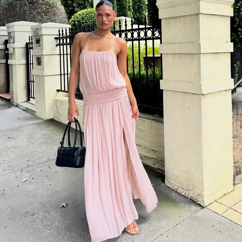 Woman wearing a pink maxi dress with spaghetti straps and a high slit