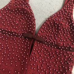 Close-up of pearl embellishments and bow detail on red formal gown