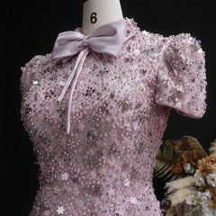 Pink sequin dress with a bow on a mannequin against a black background