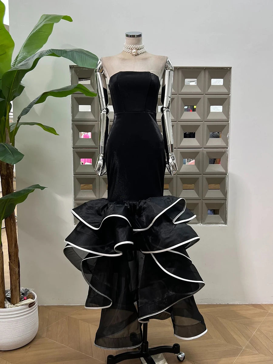 Black strapless dress with ruffled layers on a mannequin against a neutral background
