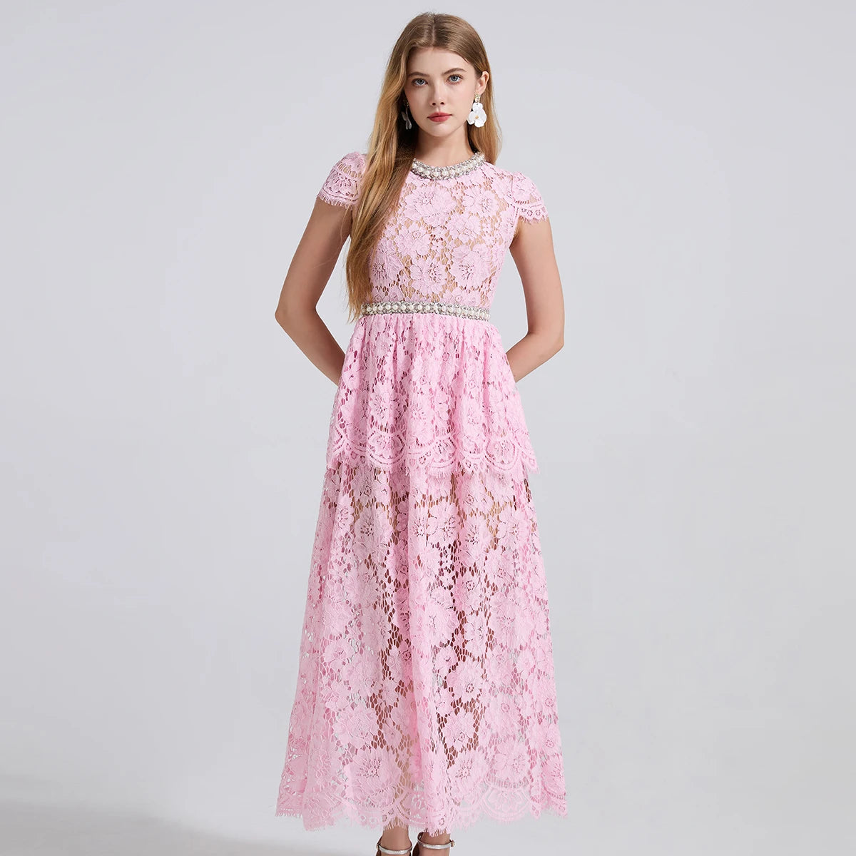 Woman wearing a pink lace dress on a gray background