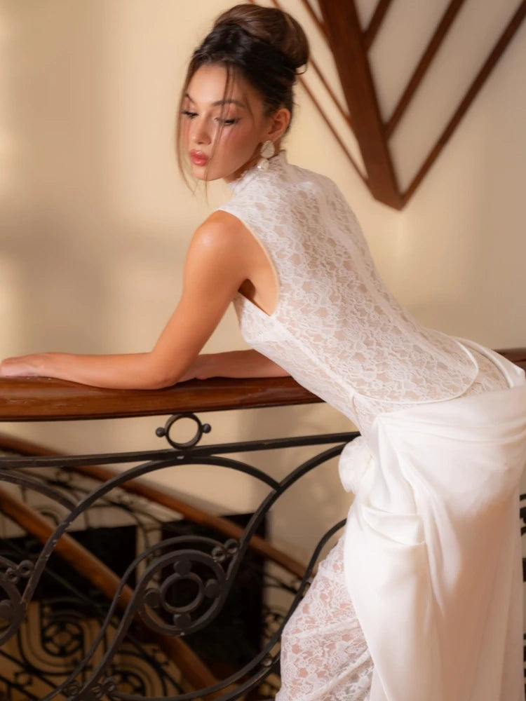 Woman in a white lace dress sitting on a staircase.