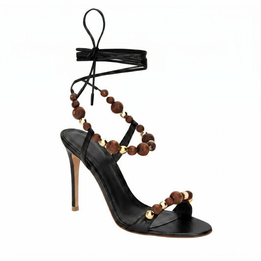 Black leather lace-up stiletto heeled sandals with wooden and gold bead embellishments.