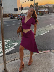 Woman posing in a purple v-neck crop top and ruched midi skirt set on a street