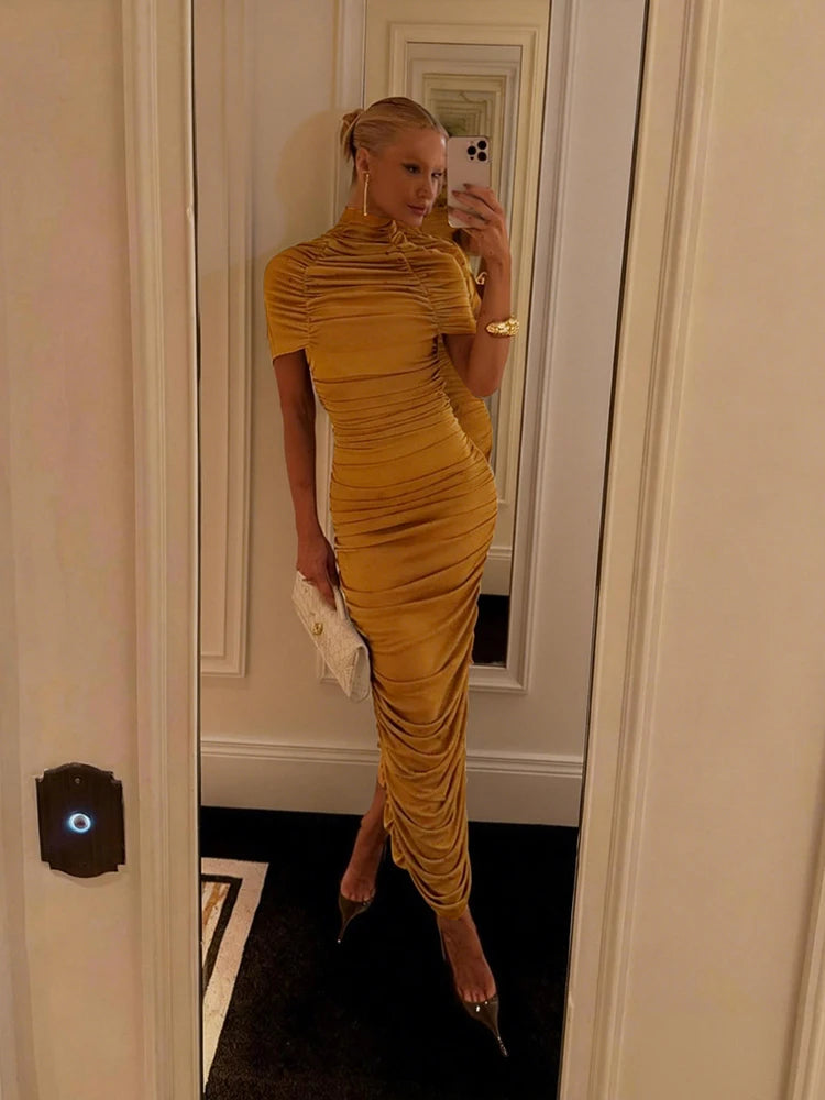 Woman in a yellow dress taking a mirror selfie in an indoor setting.