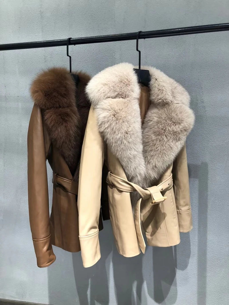 Two leather jackets with fur collars hanging on a rack against a gray background.