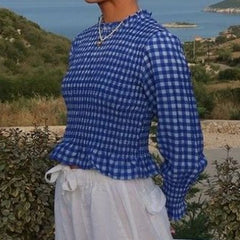 Person wearing a blue and white checkered shirt with a scenic background