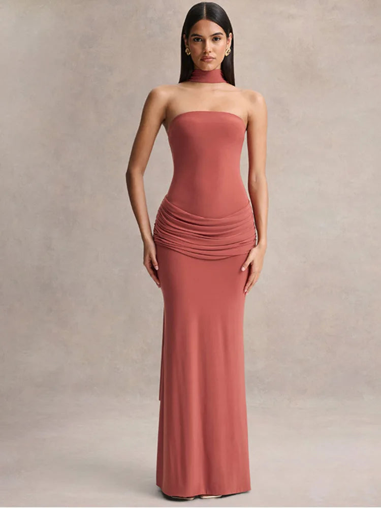 Woman wearing a strapless, floor-length rust-colored dress against a neutral background