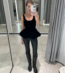 Woman taking a mirror selfie wearing a black top and black pants in a store.