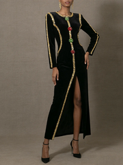 Black dress with gold trim and floral embellishments on a gray background