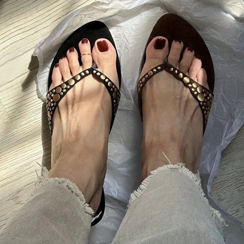 Feet wearing black and brown studded thong kitten heel sandals