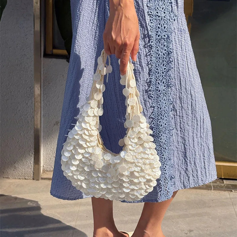 Person holding a white shell-handled bag with a blue dress.