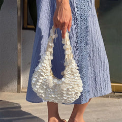 Person holding a white shell-handled bag with a blue dress.