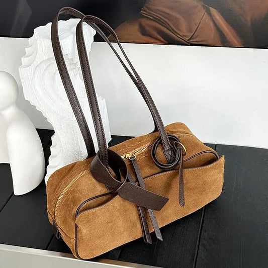Brown handbag with brown straps on a black surface