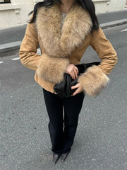 Person wearing a tan coat with fur collar and cuffs on a street.