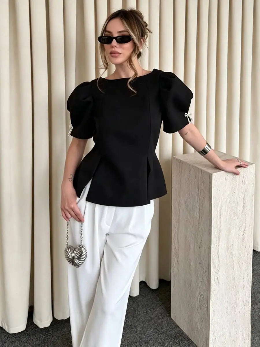 Model posing in black puff sleeve peplum blouse