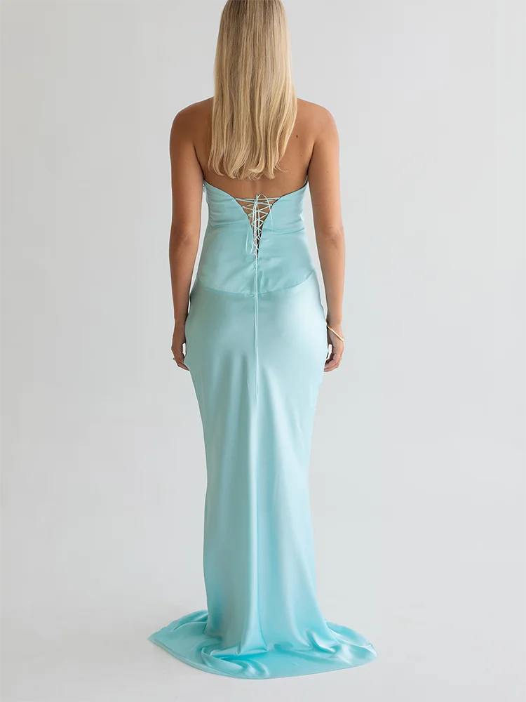 Woman wearing a light blue strapless gown with a lace-up back on a plain background