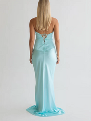 Woman wearing a light blue strapless gown with a lace-up back on a plain background