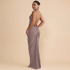 Woman wearing a long, elegant dress with a draped back on a beige background