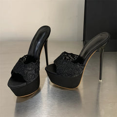 Black high-heeled shoes with platform sole on a reflective surface