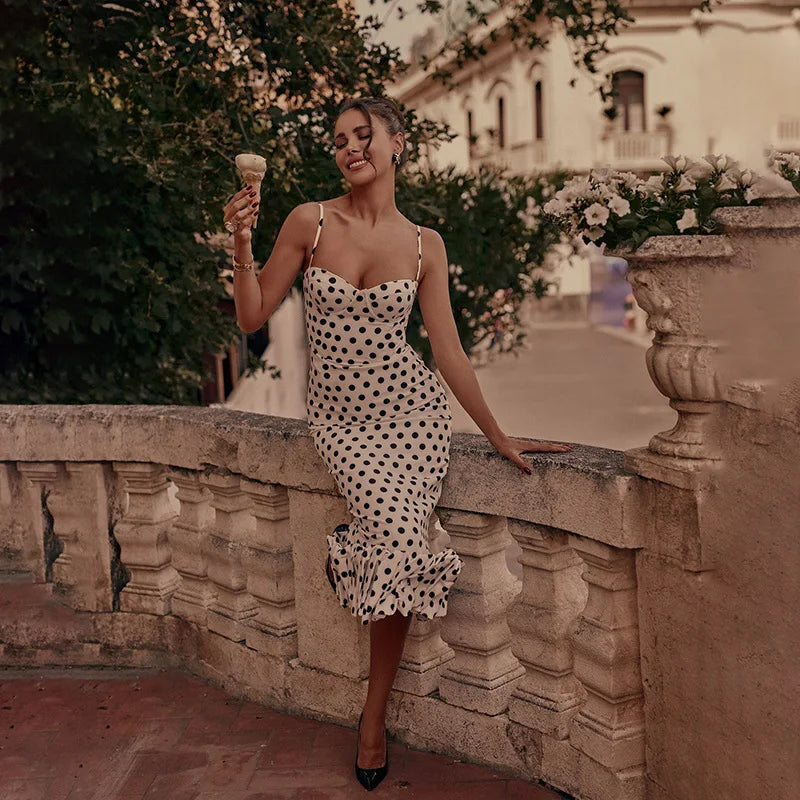Woman in a polka dot dress holding an ice cream cone in an outdoor setting.