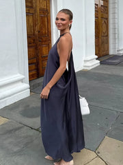 Woman in a navy blue dress standing on a stone pavement with a white building in the background.