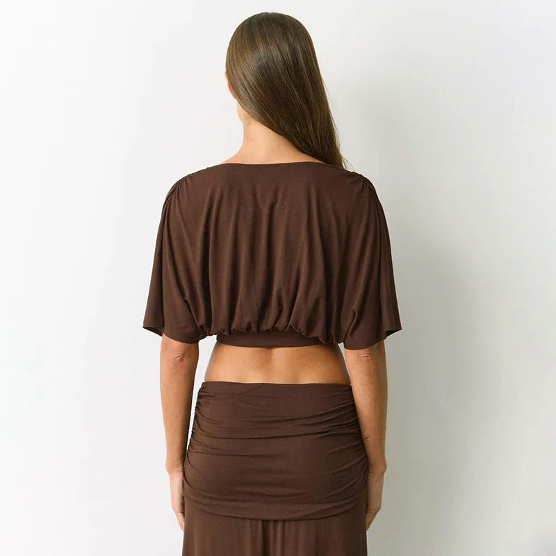 Woman wearing a brown top and skirt set against a white background