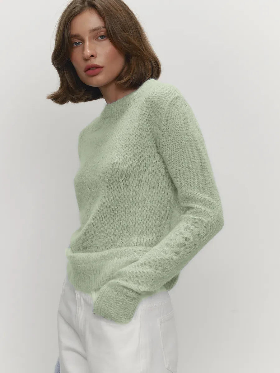 Woman wearing a light green sweater against a white background