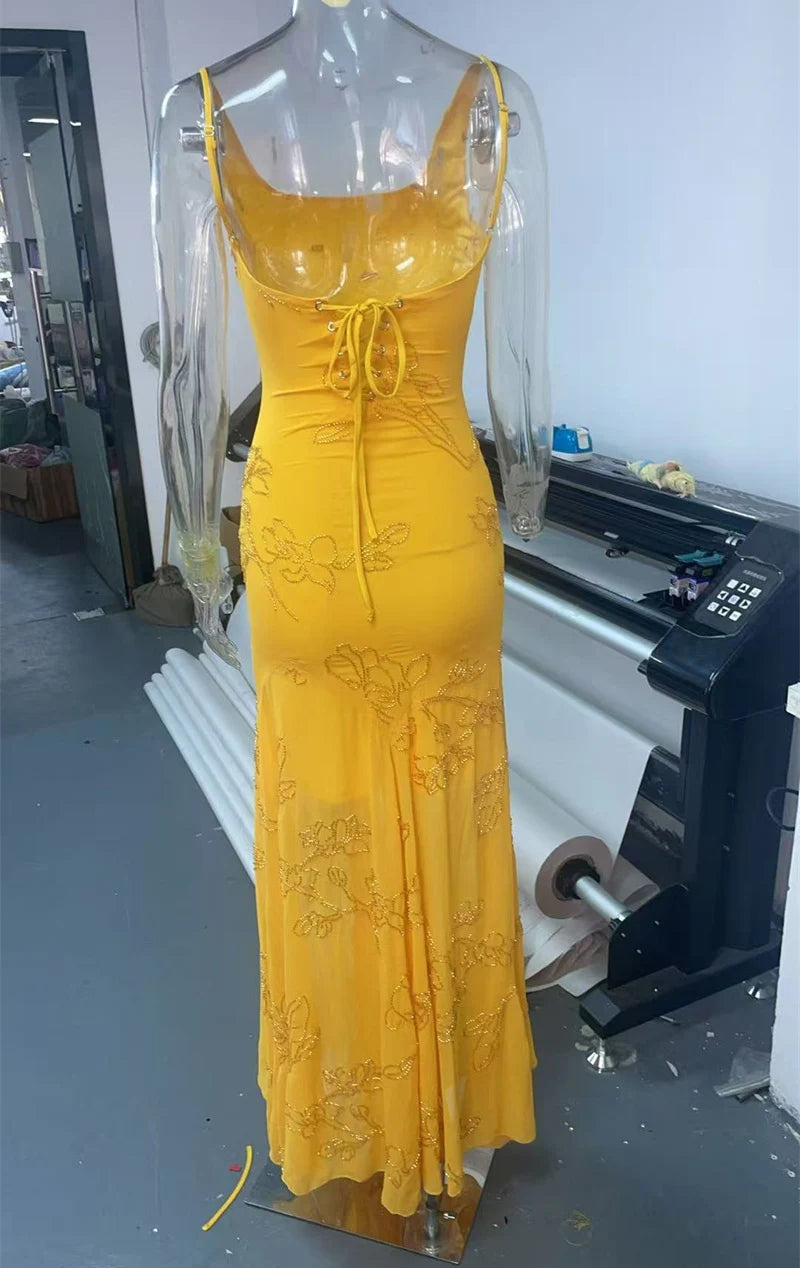 Yellow lace dress on a mannequin in an indoor setting with equipment in the background