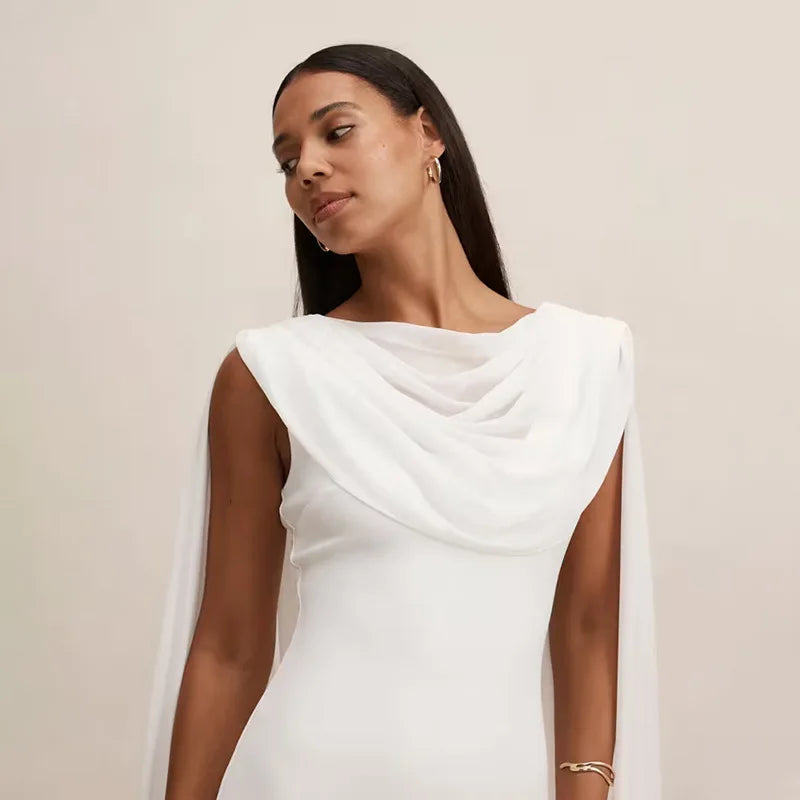 Woman wearing a white draped dress against a beige background