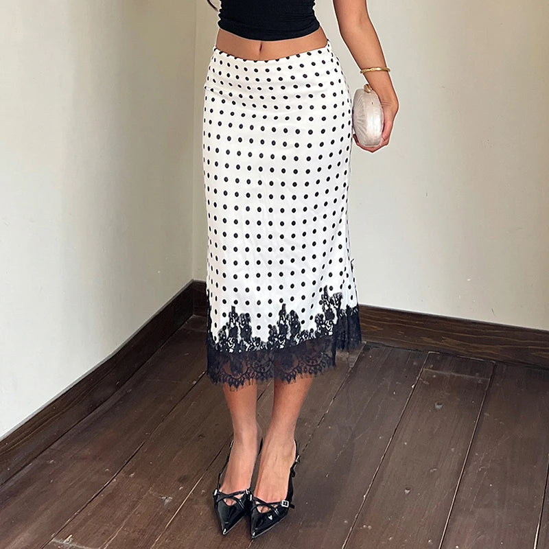 Person wearing a white polka dot skirt with black lace trim indoors.