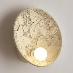 A round French wall sconce with a milk white glass lampshade, casting a soft glow in a cozy bedroom. A