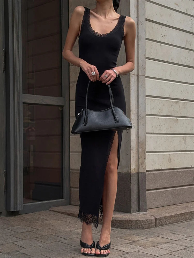 Woman in a black dress holding a black handbag outside a building.
