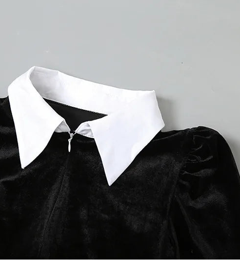 Black velvet garment with a white collar on a gray background