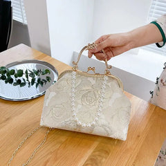 A photo of the clutch held in a woman's hand, demonstrating its size and the delicate shell lock closure.