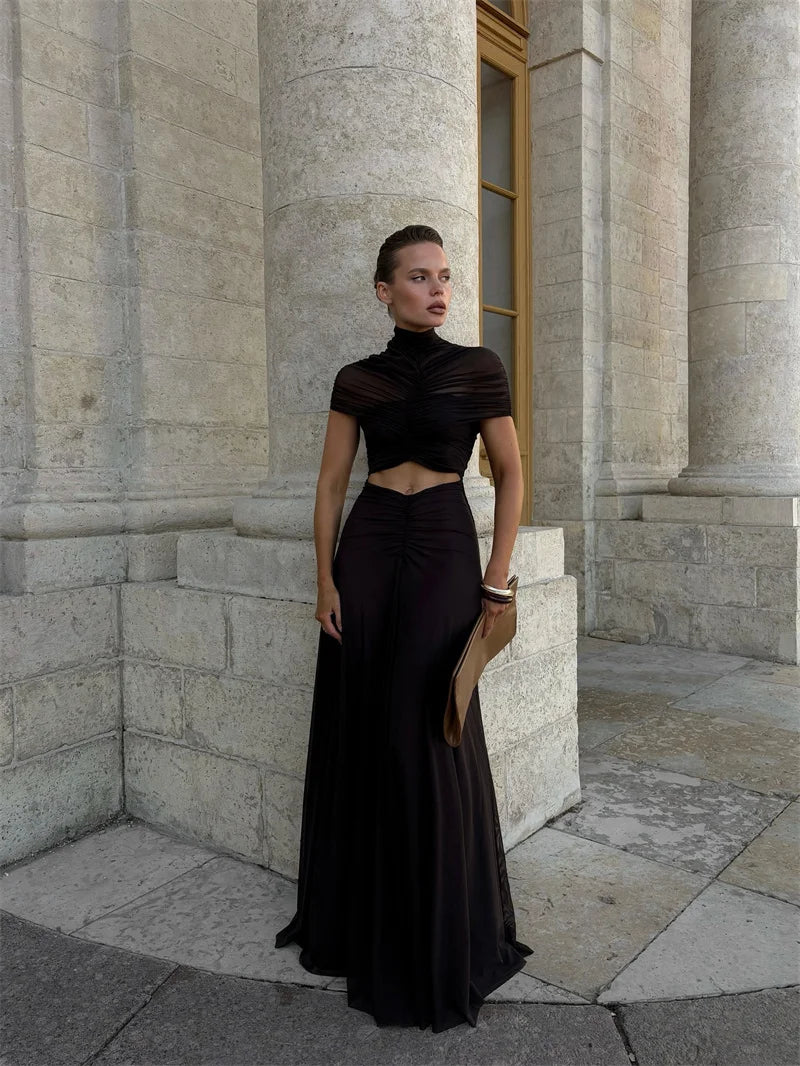 Woman in a black dress standing against a stone building