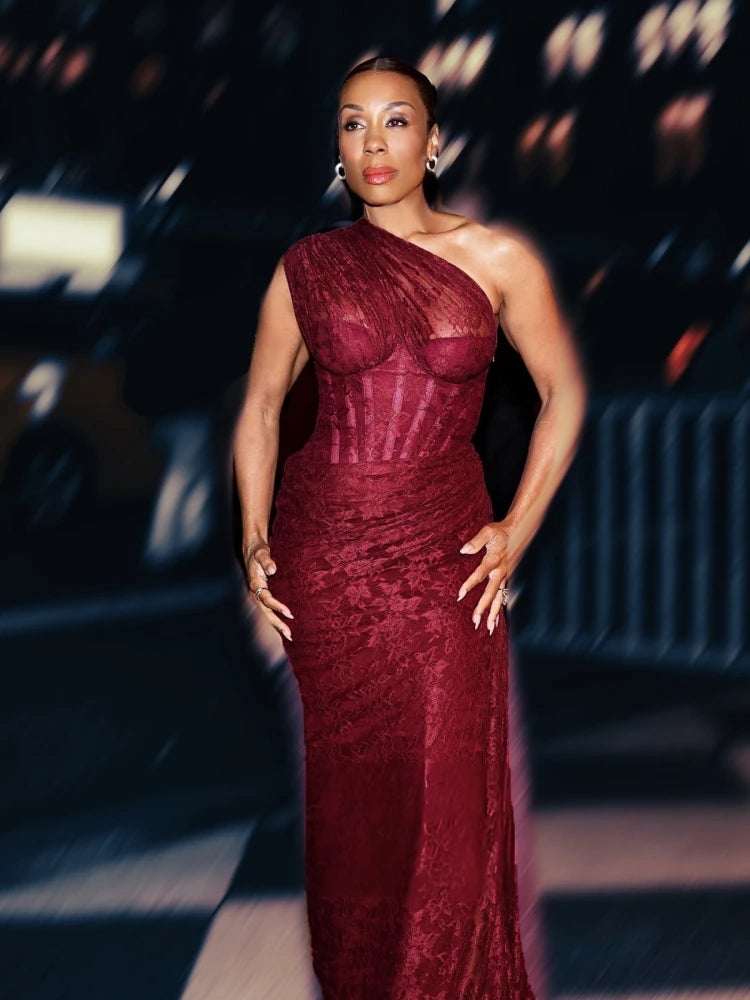 Woman in a burgundy evening gown standing against a blurred indoor background