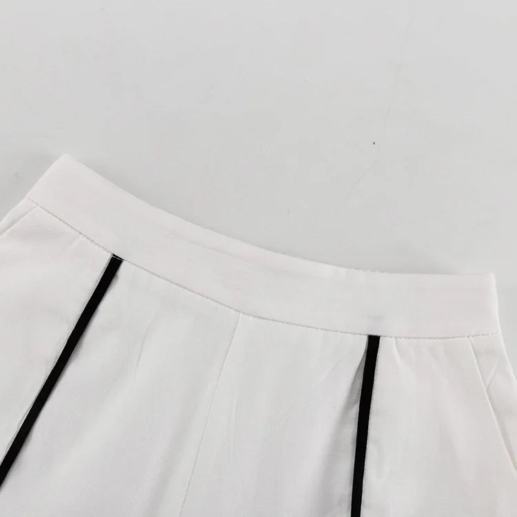 Close-up of a white skirt with black pleats on a light gray background