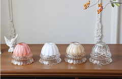 Four glass candle holders on a wooden surface with a decorative background.