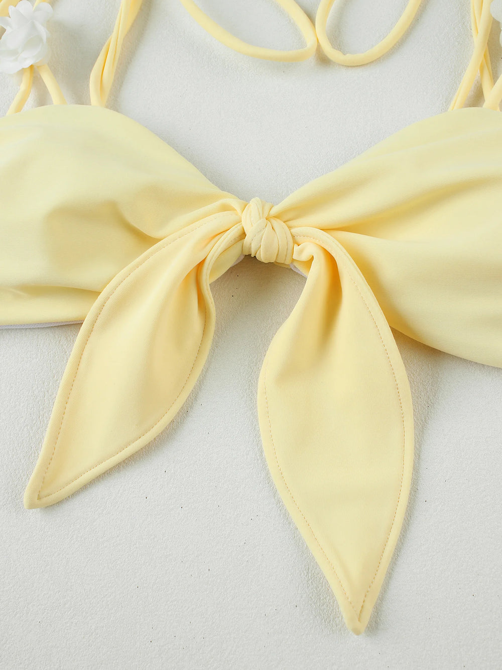 Close-up detail of bow tie closure on yellow bikini top