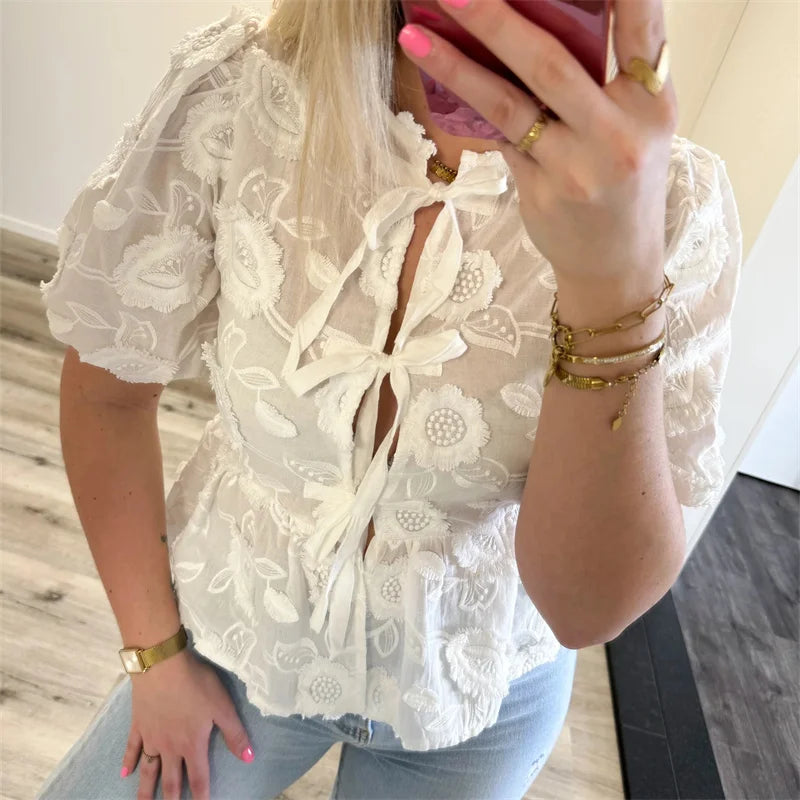Person wearing a white lace blouse with a blurred background