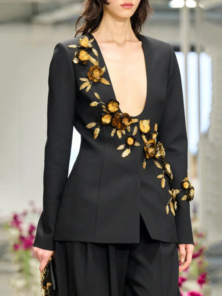 Black blazer with gold floral embroidery worn by a model in an indoor setting.