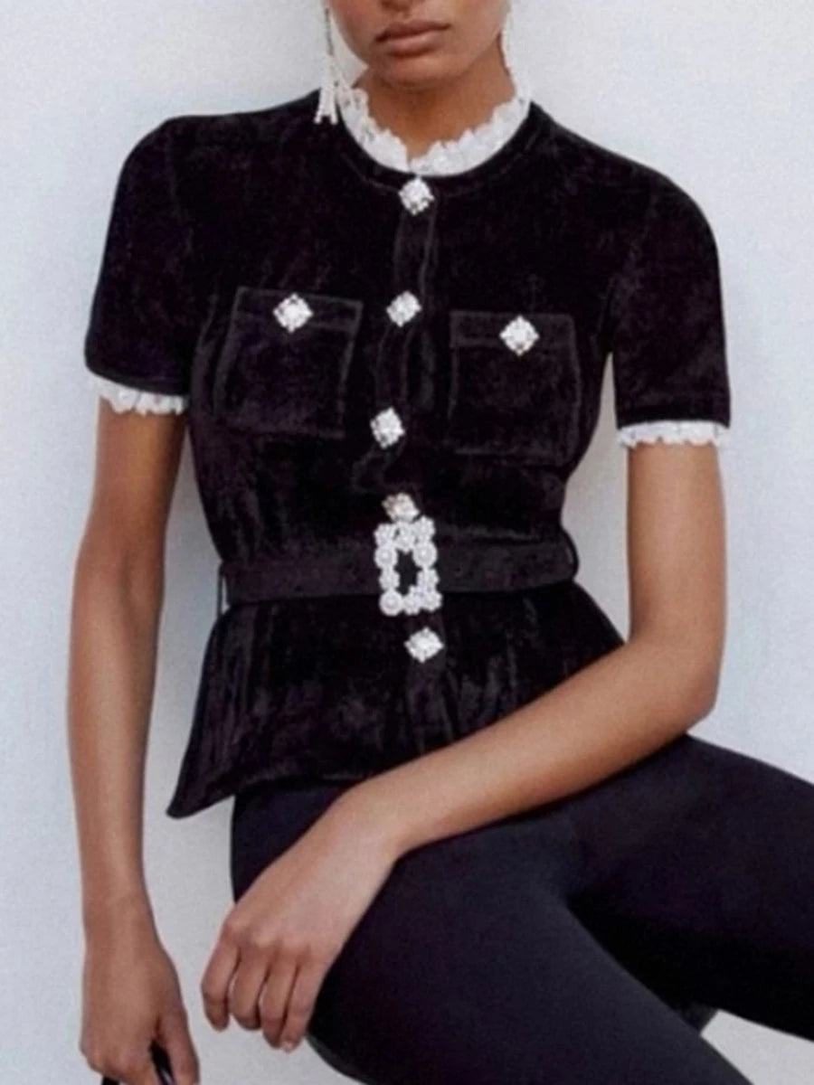 Black velvet top with white lace details worn by a model against a white background