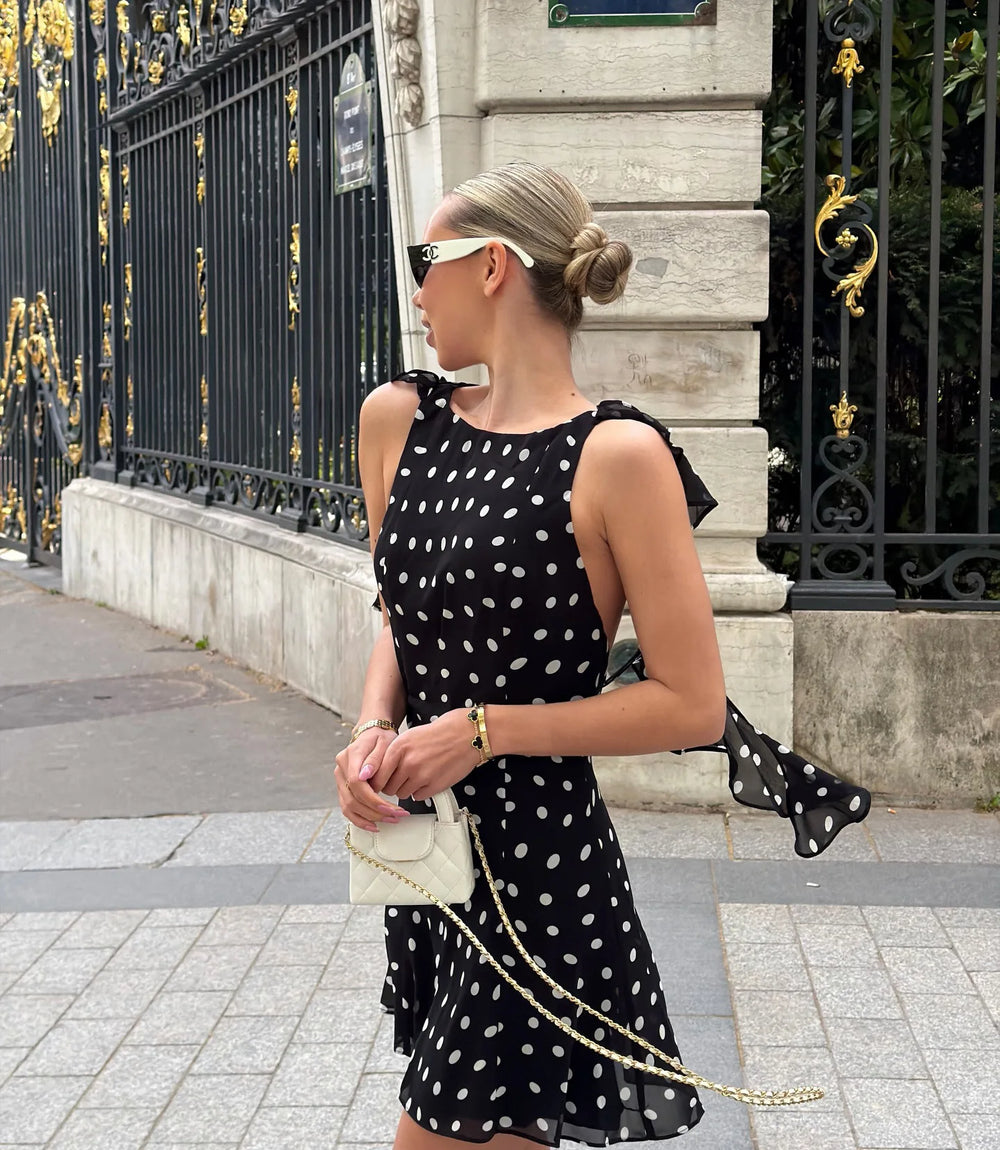 Model wearing black polka dot mini dress with a handbag