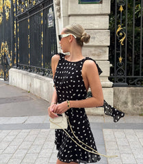 Model wearing black polka dot mini dress with a handbag