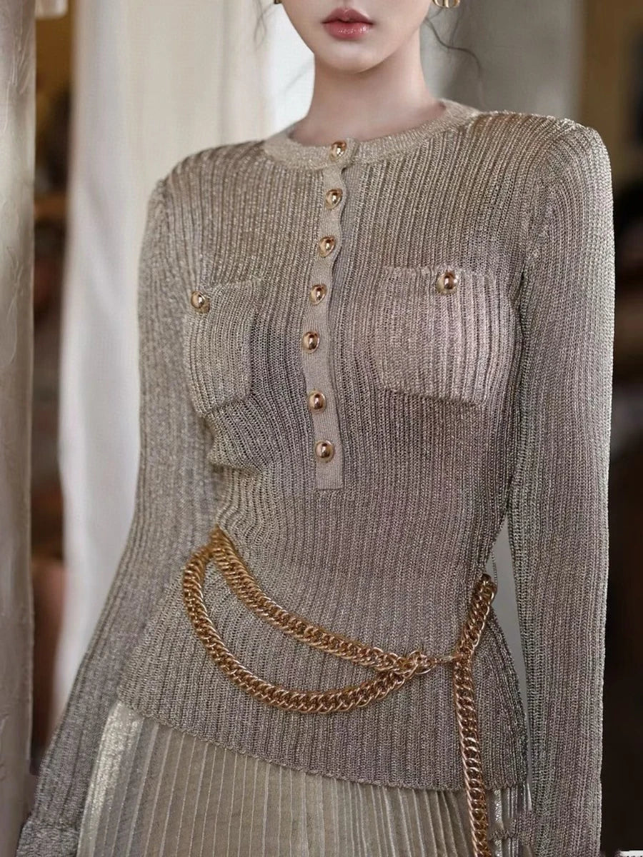 Person wearing a detailed knit sweater with gold buttons and a chain belt.