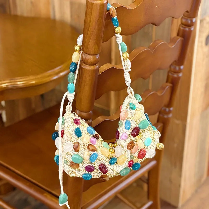 Beaded stone shoulder bag with multicolor embellishments on a wooden chair.