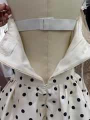 White dress with black polka dots and a visible brand label on a neutral background
