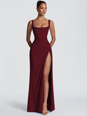 Woman wearing a burgundy evening gown with a high slit on a white background