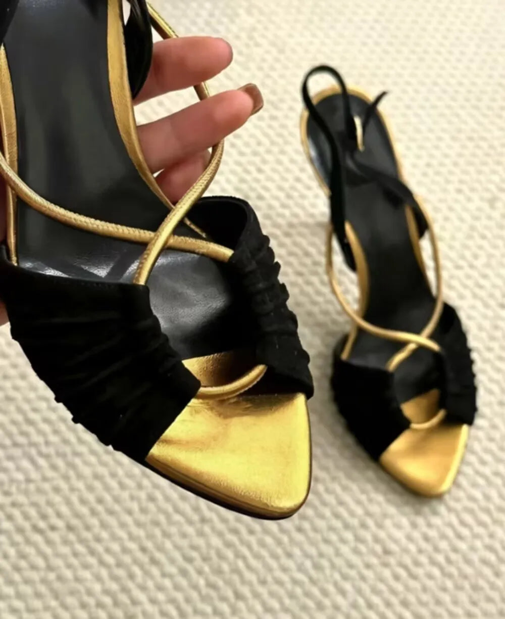 Close-up on the front of black and gold stiletto heeled sandals